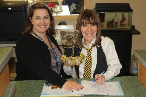 Author Elly & Schmitty The Weather Dog signing a book for the South End School library with Principal Nattrass.